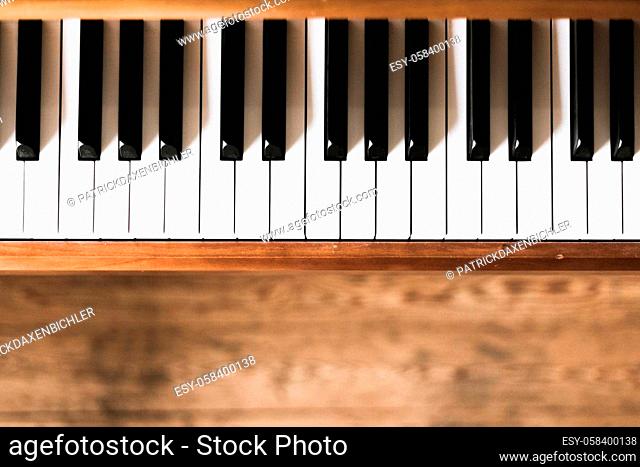 Vintage wooden piano. Keys in the foreground, wooden floor in the blurry background