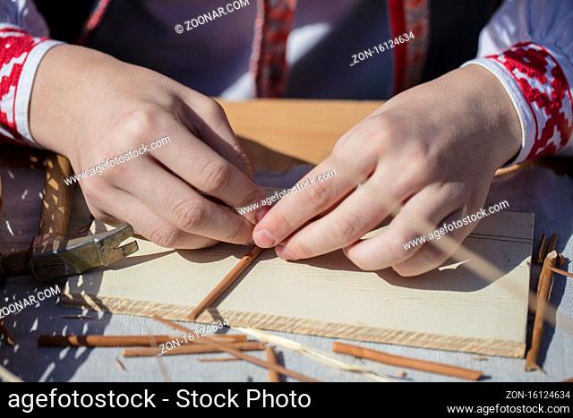 The hands of an artisan make a craft from straw. Hand made product