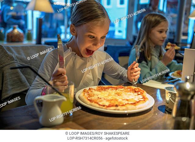 A child about to eat a delicious pizza in a restaurant
