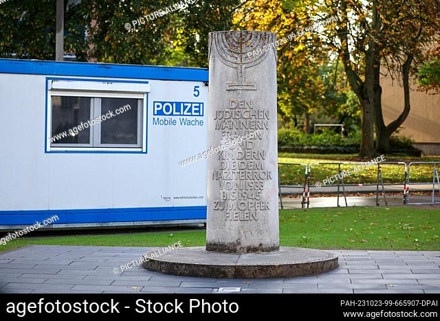 22 October 2023, Saxony-Anhalt, Dessau-Roßlau: A mobile police station stands next to a stone column commemorating the Old Synagogue and the members of the...