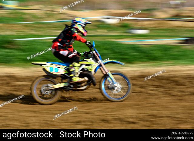 Unrecognized athlete riding a sports motorbike on a motocross racing event. Exreme sports high speed