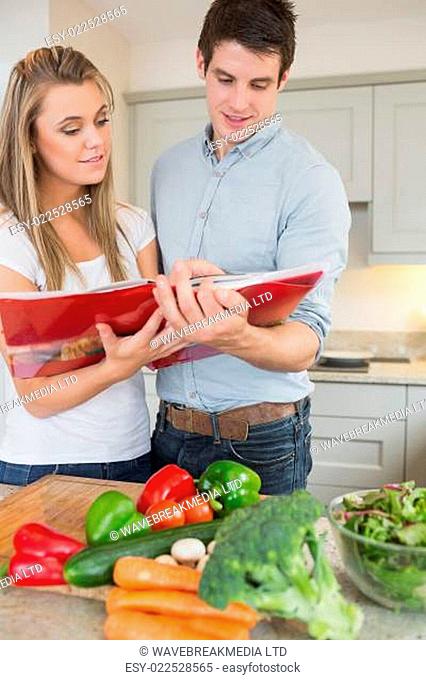 Couple reading cookbook together in kitchen
