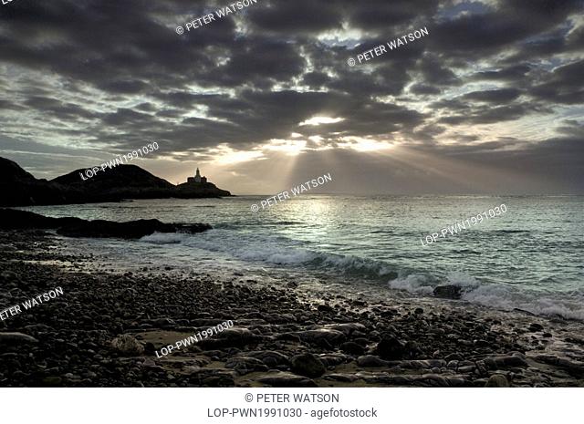 Wales, Swansea, Mumbles Point. Rays of sunlight bursting through storm clouds over Mumbles Point at dawn