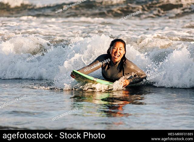 Cheerful woman surfing amidst wave in sea, Gran Canaria, Canary Islands