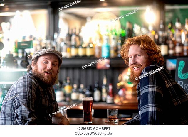 Two male customers looking over their shoulders from bar in traditional Irish public house