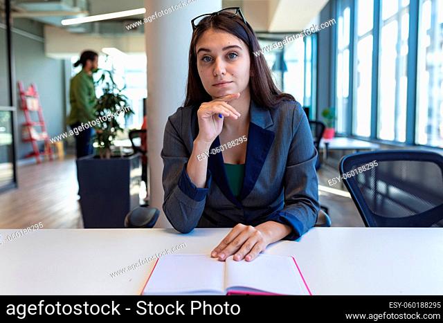 Portrait of caucasian female creative worker sitting at desk looking at camera