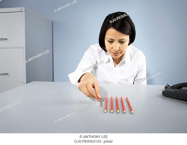 Businesswoman carefully lining up pencils