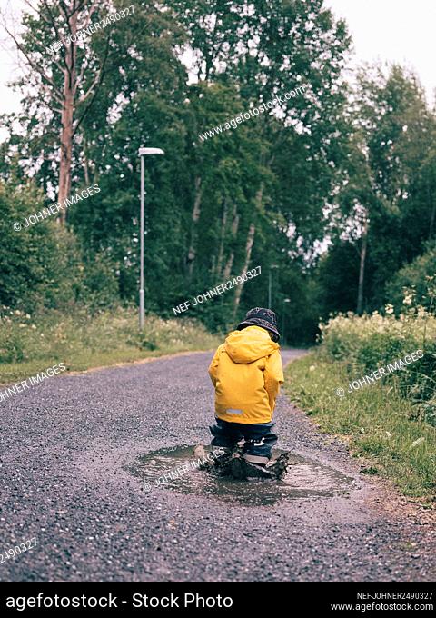 Toddler splashing in puddle