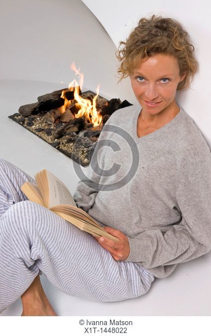 Woman sitting by fireplace, reading