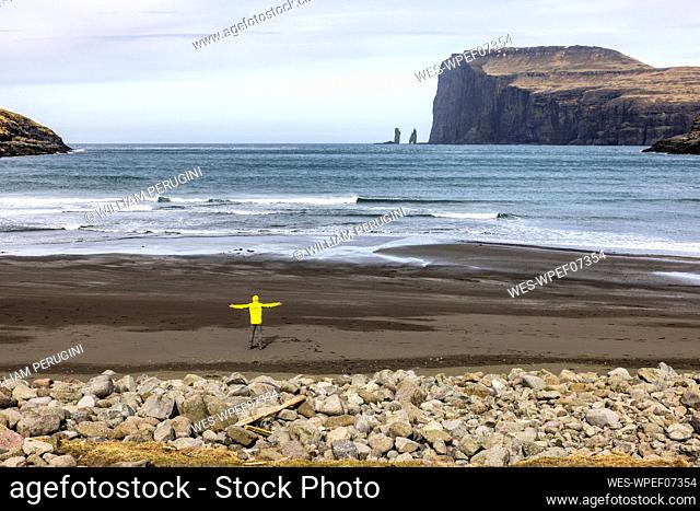Man looking at sea stacke Risin and Kellingin standing on beach