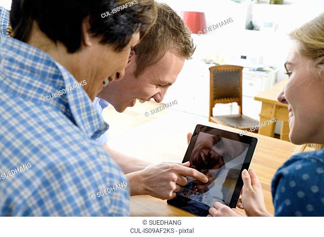 Grandmother and adult grandchildren using distortion on digital tablet