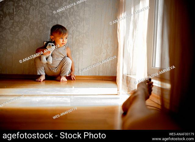 Boy with stuffed toy in squatting position at home