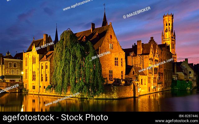 Panorama of Bruges tourist landmark attraction, Rozenhoedkaai canal with Belfry and old houses along canal with tree in the night