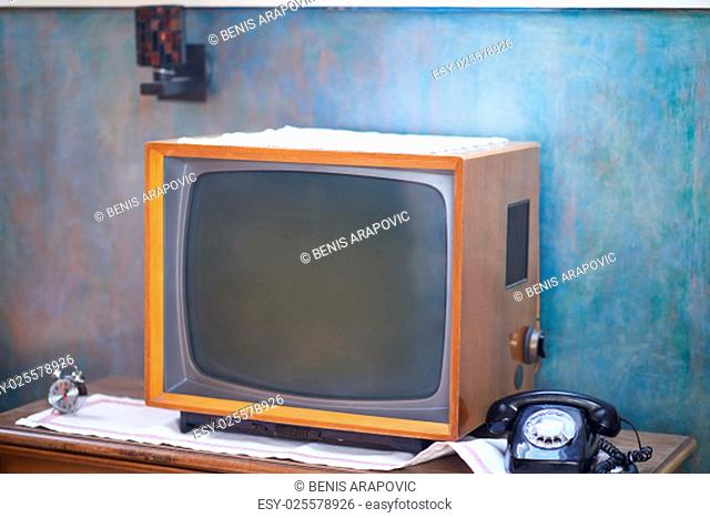 Vintage retro look living room detail. Television, telephone and clock on wooden old table