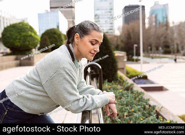 Woman leaning on railing standing at office park
