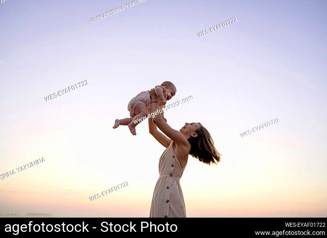 Happy mother playing with daughter during sunset