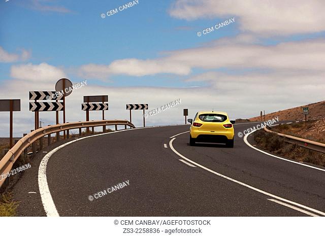 Yellow car on the mountain road with traffic signs by side, Fuerteventura, Canary Islands, Spain