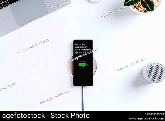 smartphone charging on wireless charger white table background