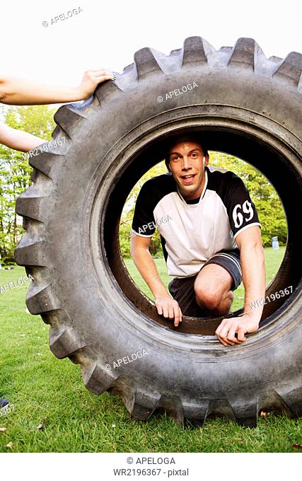 Portrait of man looking through tire at park