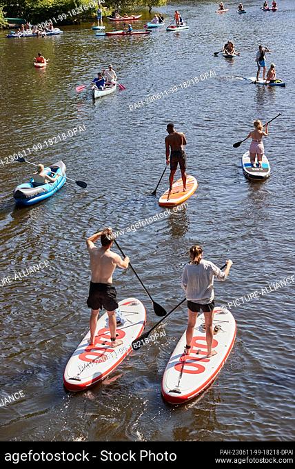 11 June 2023, Hamburg-Winterhude: Stand-up paddlers and rowers enjoy their outing on a canal of the Außenalster in Hamburg-Winterhude on Sunday in summery warm...