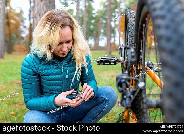 Woman with blond hair repairing bicycle at Cannock Chase