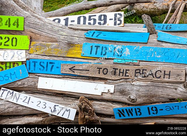 Log boom identification labels and a sign to the beach on a driftwood log in Garry Point Park Steveston British Columbia Canada