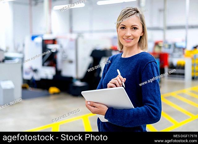 Portrait of smiling businesswoman holding digital tablet in factory