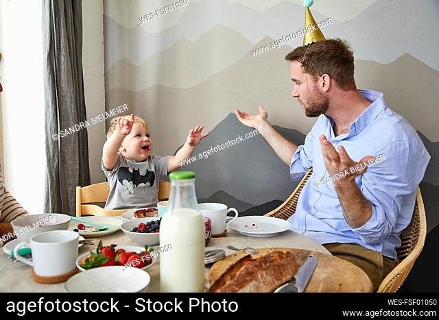 Father and little son having fun at breakfast table