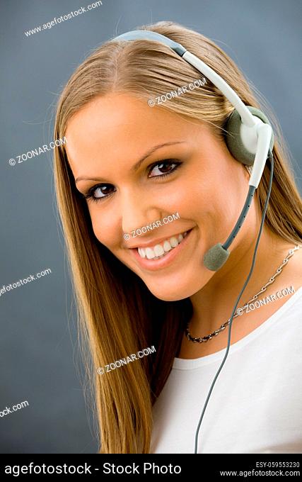 Studio portrait of happy young female customer service operator talking on headset. Isolated