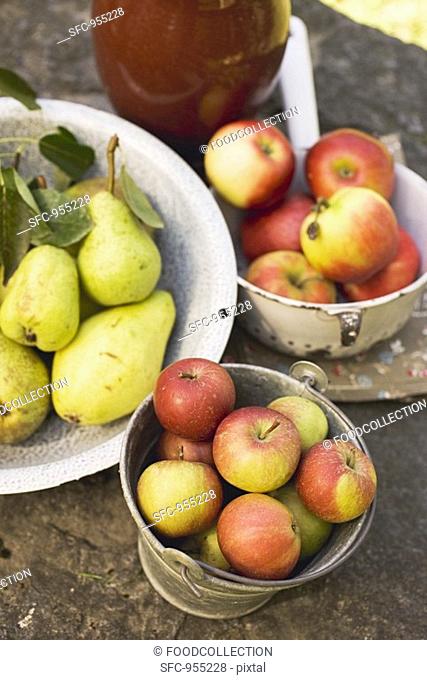 Fresh pears and apples in containers on stone wall