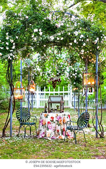 A table setting under a rose arbor with a fence in the background.Georgia USA