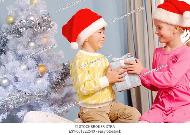 Portrait of happy siblings holding Christmas gifts and looking at each other