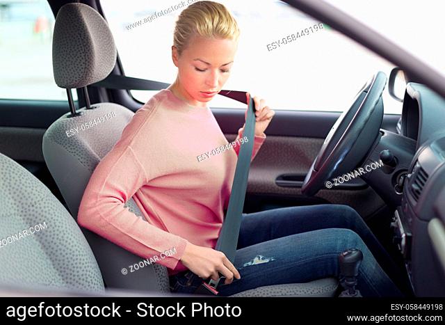 Safety first. Beautiful blonde caucasian lady fastening car seat belt