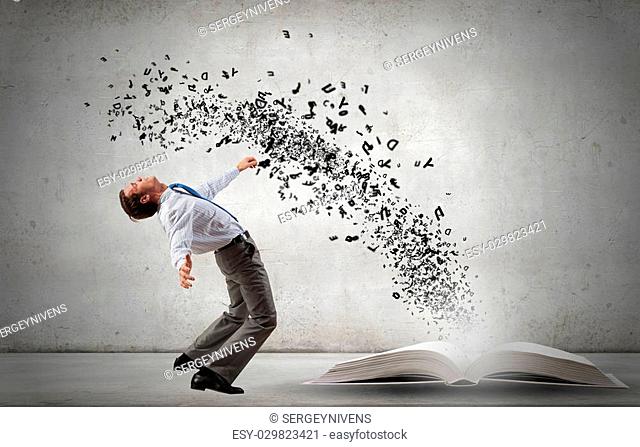 Young man benting to evade characters flying from book