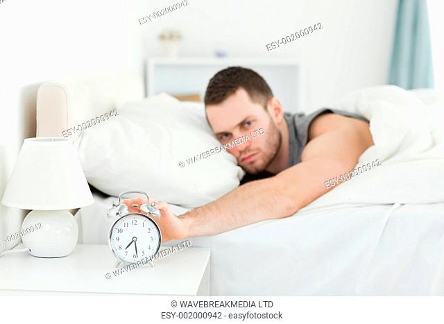 Man being awakened by an alarm clock in his bedroom