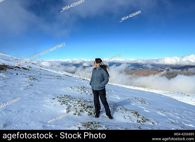 latina woman on mountaintop above the clouds,