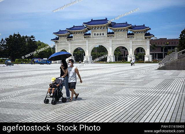 A couple with a baby in a stroller walks through the entrance gate to Liberty Square in front of the of Chiang Kai-shek Memorial Hall in Taipei in Taipei