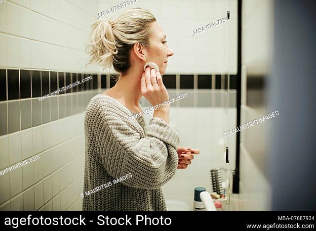 Woman in the bathroom, cleans her face