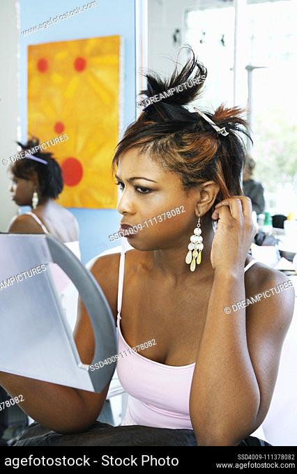 Young woman examining herself in the mirror
