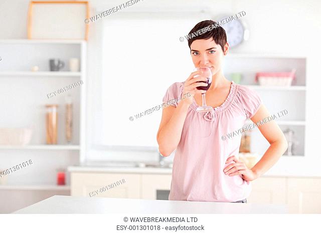 Joyful woman drinking wine in a kitchen