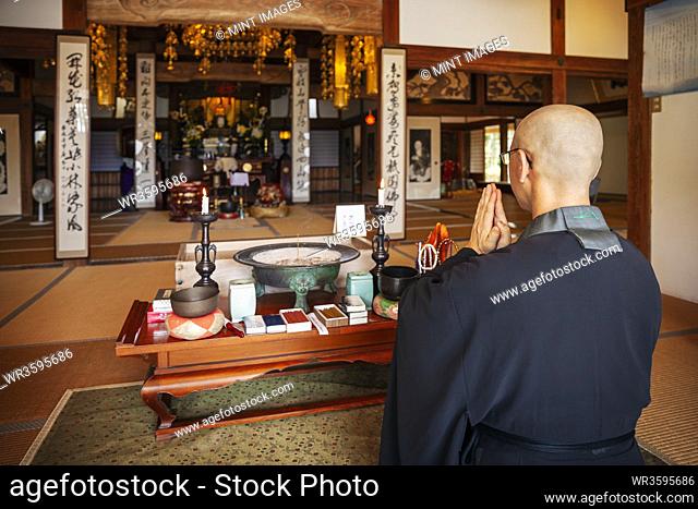 Buddhist priest kneeling in Buddhist temple, praying