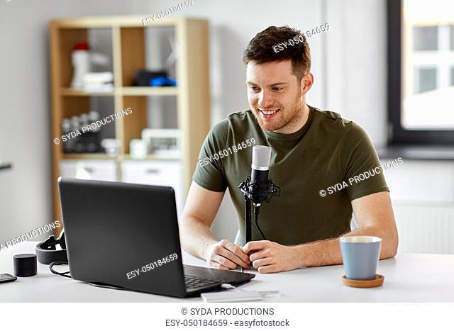 man with laptop and microphone at home office