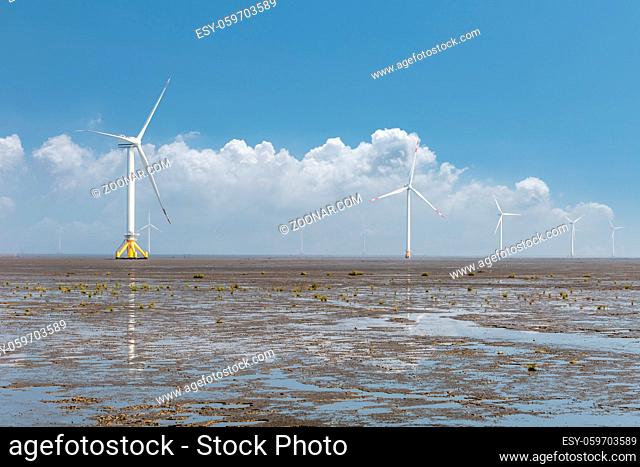 renewable energy landscape of wind farm against a blue sky on coastal mud flat