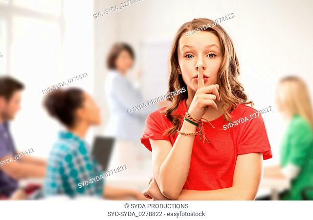 teenage girl in red t-shirt with finger on lips