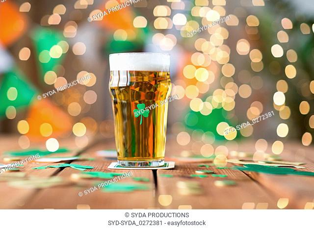 glass of beer with shamrock and coins on table