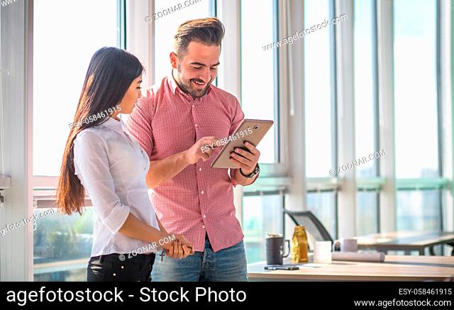 Businessman using tablet PC and smiling. Man explaining his colleague new business strategy while working in office interior. Freelance concept