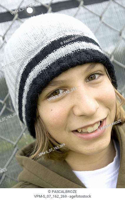 Portrait of a teenage girl leaning against a chain-link fence and smiling