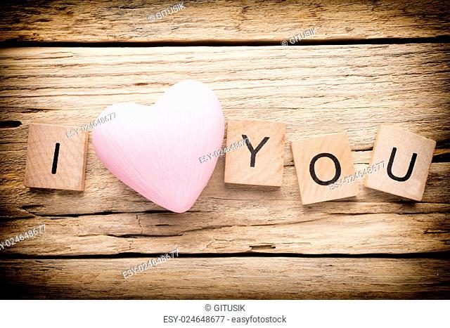 Red heart on old wooden background - Stock Image. I love you, cast out of wood kubik