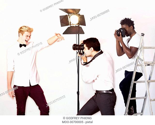 Paparazzi taking photographs of male actor over white background