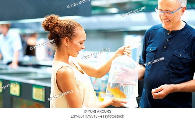 Portrait of happy female customer buying live fish from mature man
